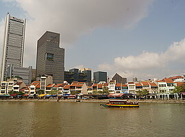 Blick von der Esplanade on the Bay auf Raffles Place mit dem Pickering Operations Complex und einem Fährboot auf dem Singapore River